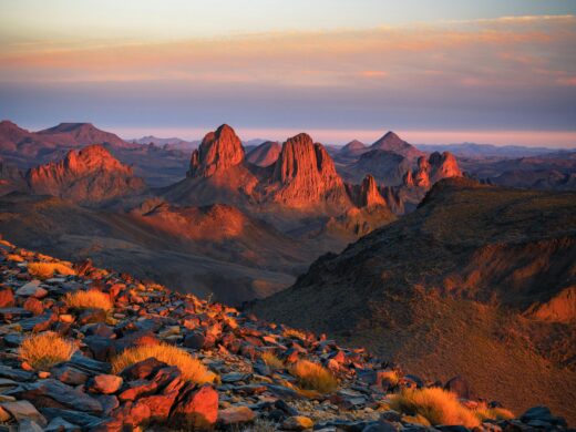 Timimoune : escale à l’oasis rouge Capture the breathtaking sunset across the rocky terrains of Tamanrasset, Algeria.